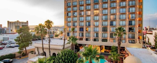 Hotel Lucerna Ciudad Juarez – fachada diurna con alberca rodeada de palmeras y área central de Zona Pronaf.
