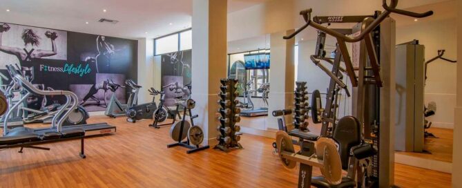 Hotel Lucerna Ciudad Juarez – gimnasio con caminadoras, bicicletas, pesas libres y equipo multifuncional sobre piso de madera.