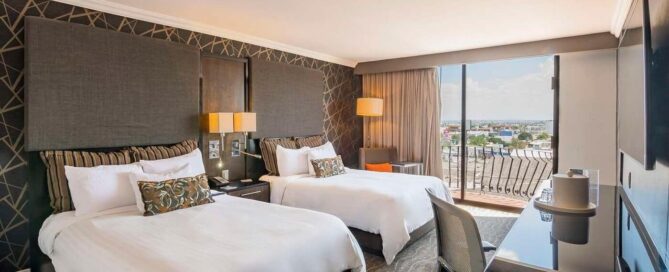 Hotel Lucerna Ciudad Juarez – habitación doble con dos camas, escritorio y balcón con vista urbana.