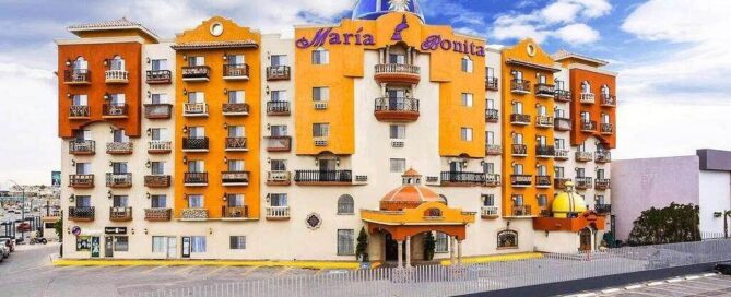 Fachada colorida de estilo colonial con cúpula azul y balcones; letrero “María Bonita” visible desde el estacionamiento.