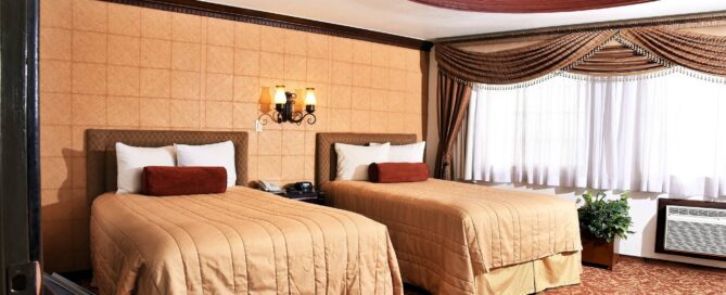 Habitación doble con dos camas matrimoniales, cabeceras tapizadas y techo decorativo, en María Bonita Business Hotel & Suites, Ciudad Juárez.