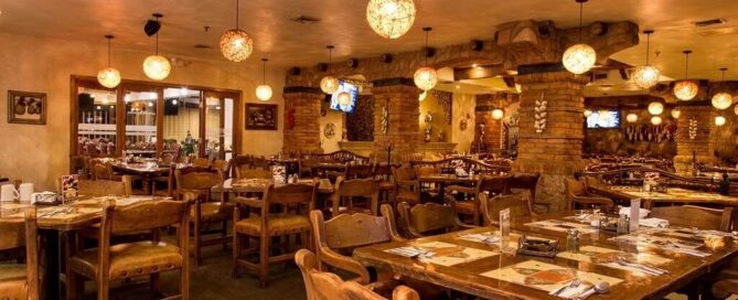 Restaurante de estilo rústico con mesas de madera y lámparas esféricas ambientales en María Bonita Business Hotel & Suites.