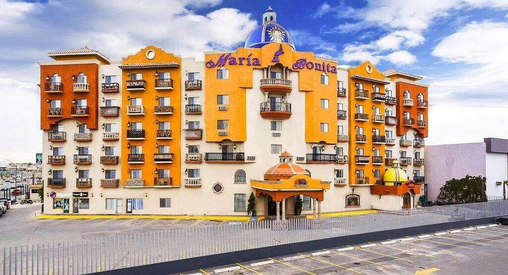 Fachada colorida de estilo colonial con cúpula azul y balcones; letrero “María Bonita” visible desde el estacionamiento.