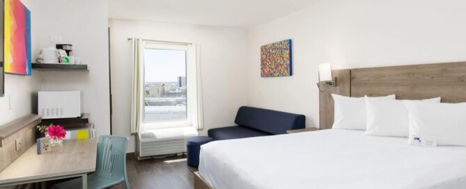 Habitación del Hotel Mesaluna con cama king, sofá, escritorio, microondas y cafetera, luz natural hacia la zona Consulado.
