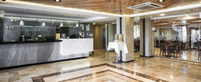Lobby del Hotel Mesaluna con recepción de mármol, techo de madera y piso tipo granito, ambiente moderno.