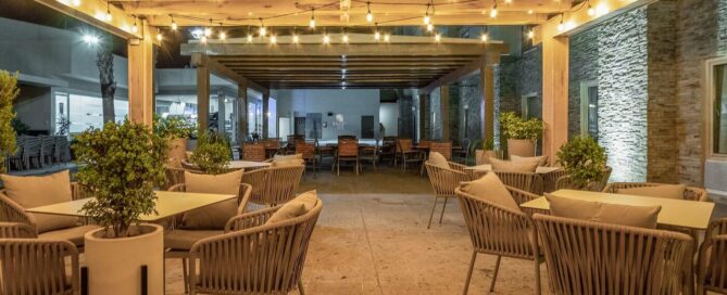 Terraza del Hotel Mesaluna con pérgola de madera, series de luces cálidas y mesas al aire libre.