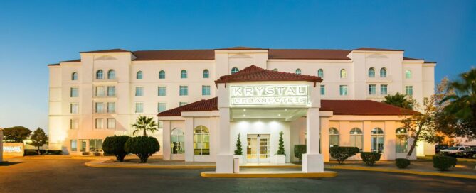 Fachada de Krystal Urban Ciudad Juárez al atardecer con marquesina “KRYSTAL URBAN HOTELS” y entrada principal.