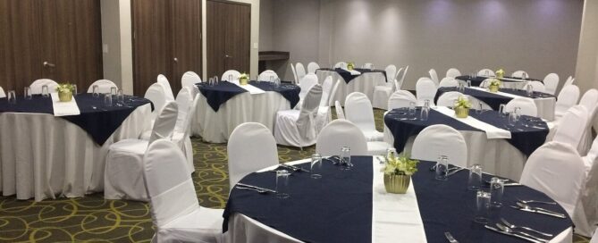 Sala de eventos de Krystal Urban Ciudad Juárez con mesas redondas montadas en mantelería azul y blanca.