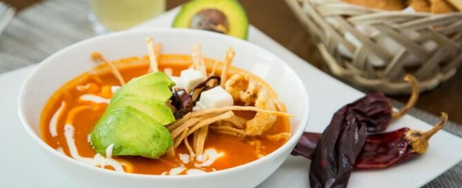 Tazón de sopa mexicana del restaurante de Krystal Urban Ciudad Juárez con aguacate, totopos y chiles secos al lado.