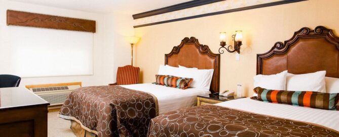 Habitación doble del María Bonita Branch Hotel Business & Suites con dos camas matrimoniales y cabeceras talladas.