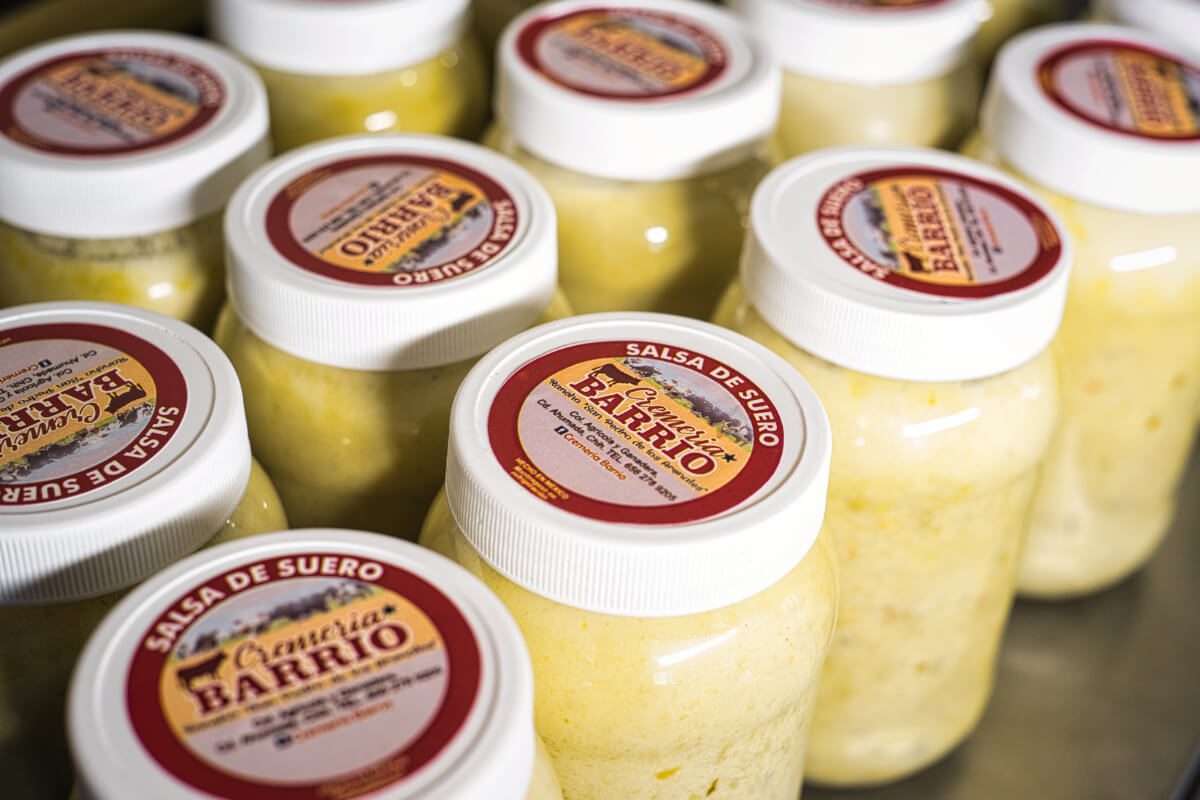 Frascos con “salsa de suero”, condimento tradicional del norte de México sobre mesa, con etiqueta visible.