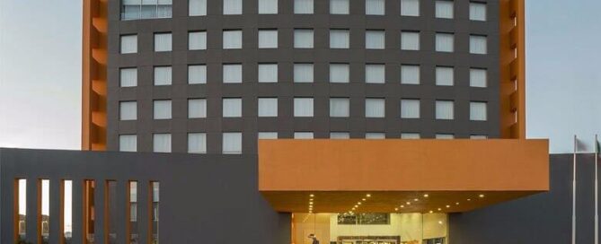 Fachada del Real Inn Ciudad Juárez con marquesina naranja y entrada principal al atardecer.