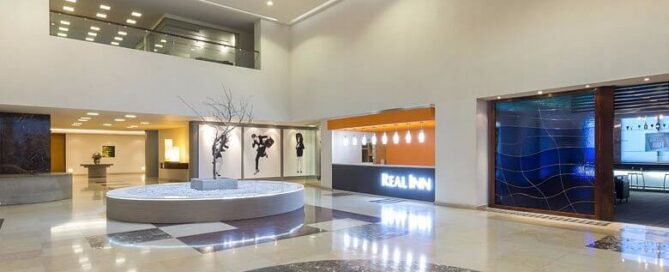 Lobby del Real Inn Ciudad Juárez con fuente central, recepción moderna y doble altura.