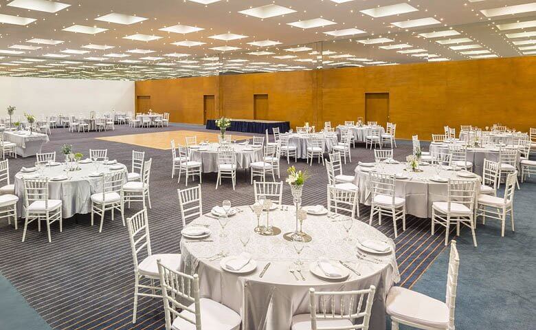 Salón de eventos del Real Inn Ciudad Juárez montado en banquete con sillas tiffany y techo de luminarias.