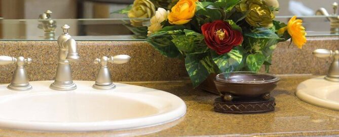 Baño con dos lavabos redondos y arreglo floral; acabados en granito en María Bonita Branch Hotel Business & Suites.
