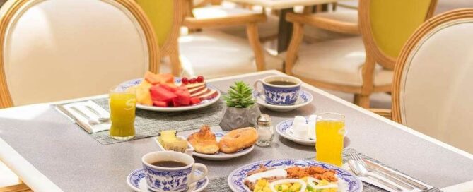 Desayuno servido en iStay Hotel Ciudad Juarez: fruta, huevos, pan dulce y jugo en vajilla azul.