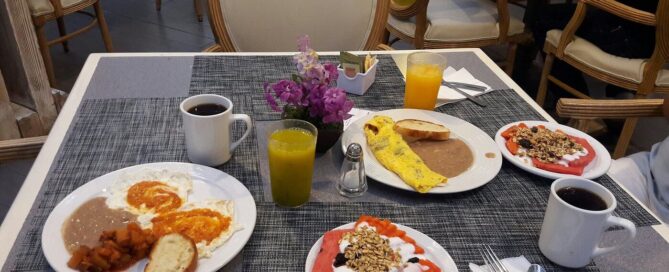 Platillos de desayuno en iStay Hotel Ciudad Juarez con omelet, café y plato de fruta con granola.