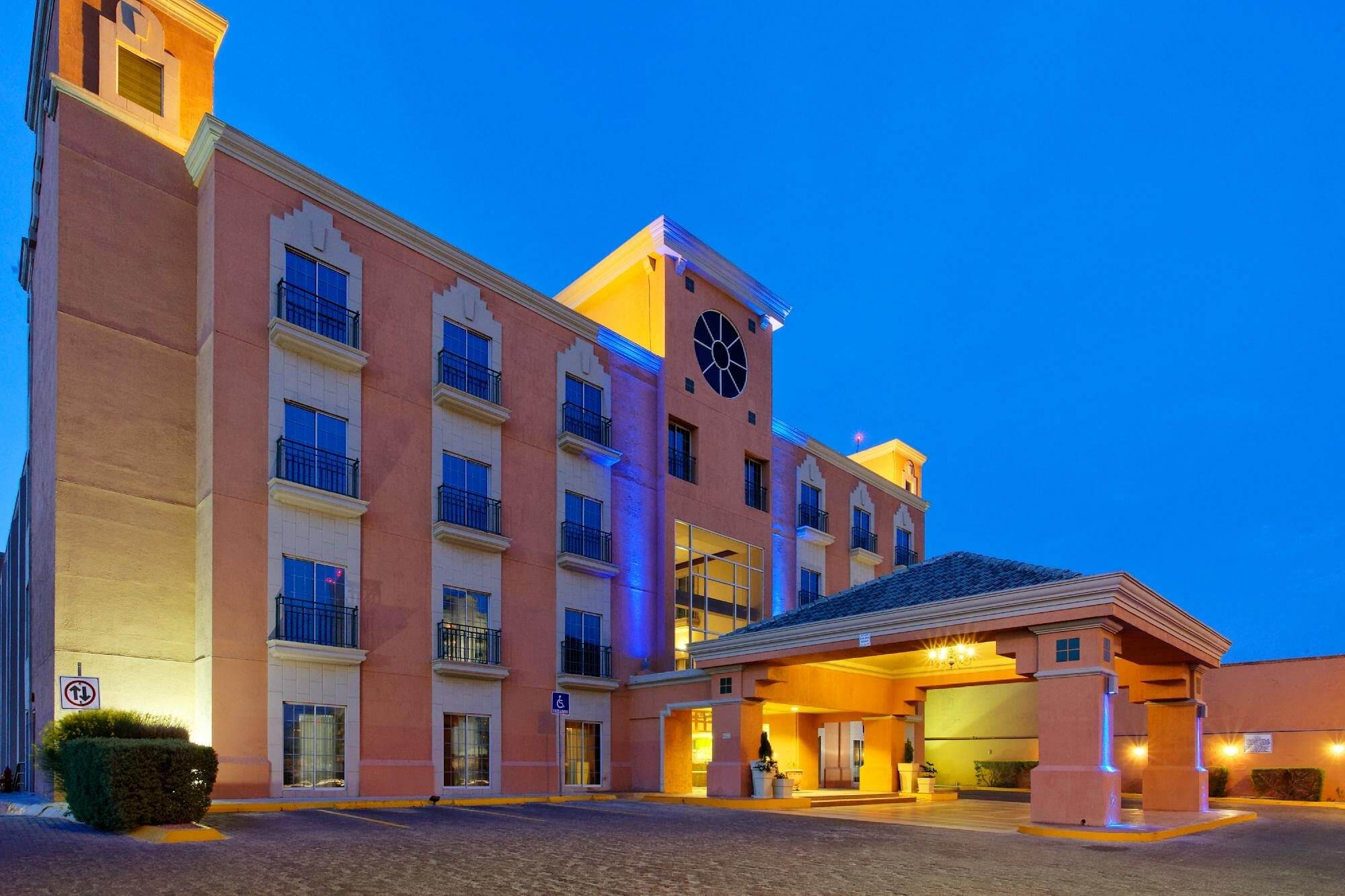 Fachada del iStay Hotel Ciudad Juarez al atardecer con pórtico de acceso y cuatro niveles.