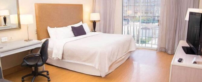 Habitación king del iStay Hotel Ciudad Juarez con escritorio ergonómico, sofá y balcón francés.