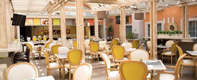 Restaurante La Pérgola del iStay Hotel Ciudad Juarez, patio cubierto con vigas de madera y sillas bistró.