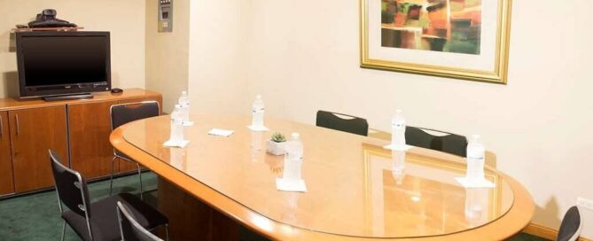 Sala de juntas del iStay Hotel Ciudad Juarez para 6–8 personas con mesa oval y pantalla.